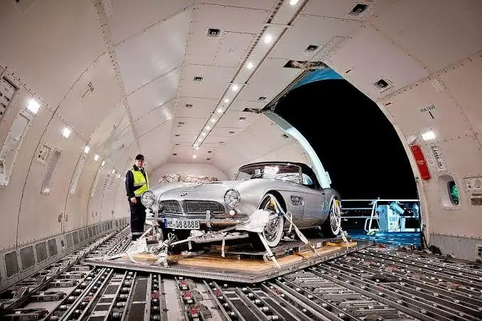 A classic car secured on a pallet inside an aircraft cargo hold