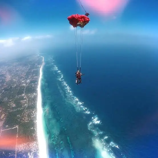 Tandem skydivers under canopy above the Diani coastline and reef